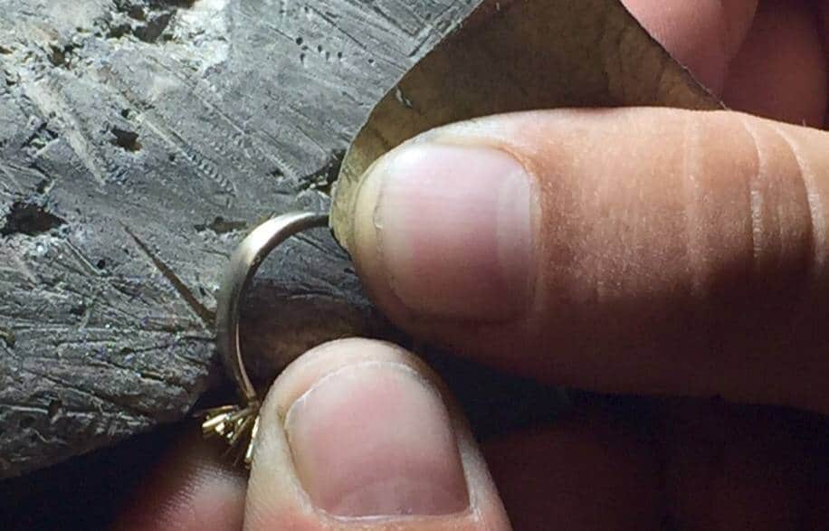 Finitura a smeriglio di un anello solitario in oro bianco sul banchetto orafo di un laboratorio